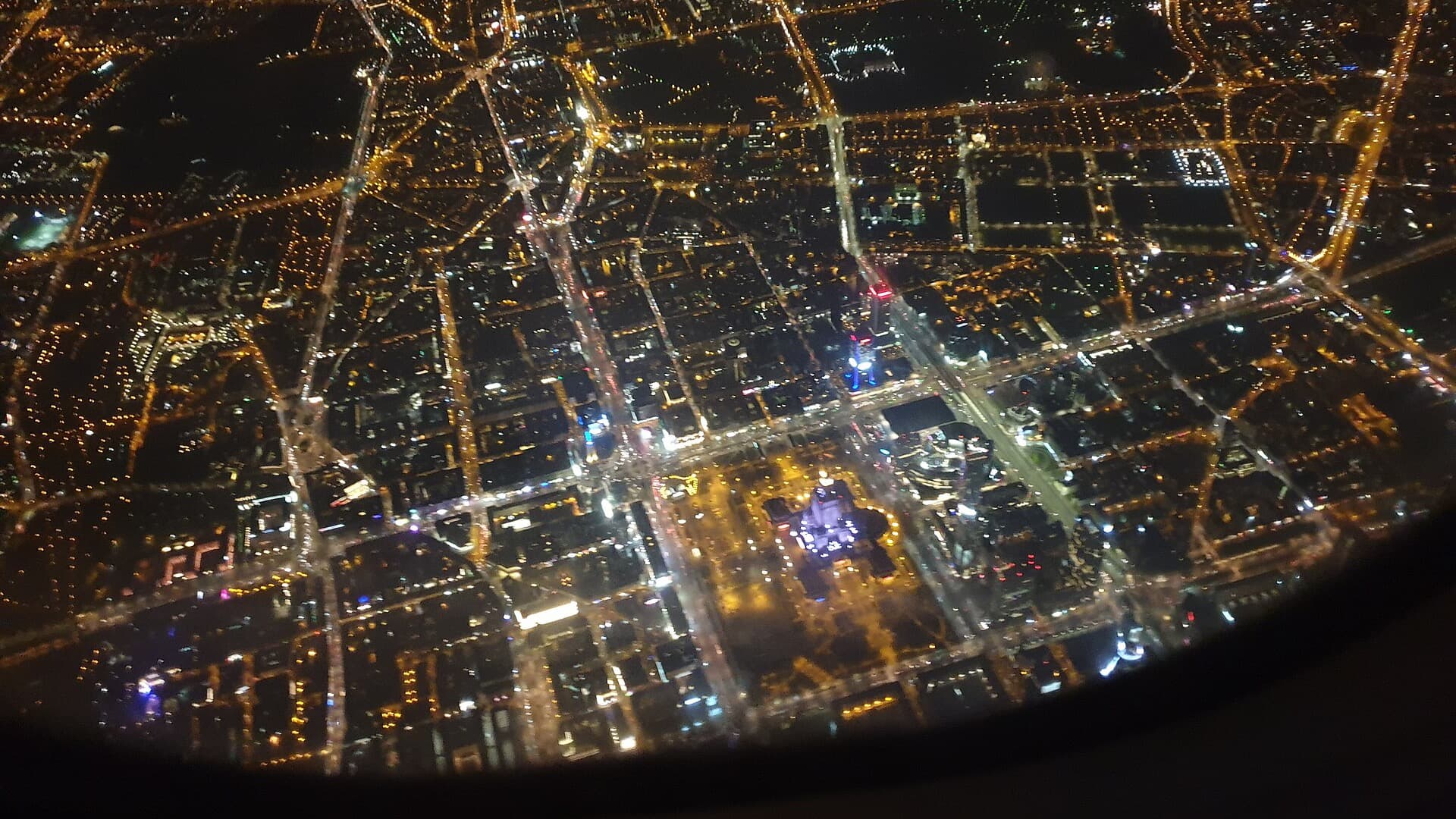 Central Warsaw at night from a plane: lit streets in a grid, the Palace of Culture and Science glowing near the bottom